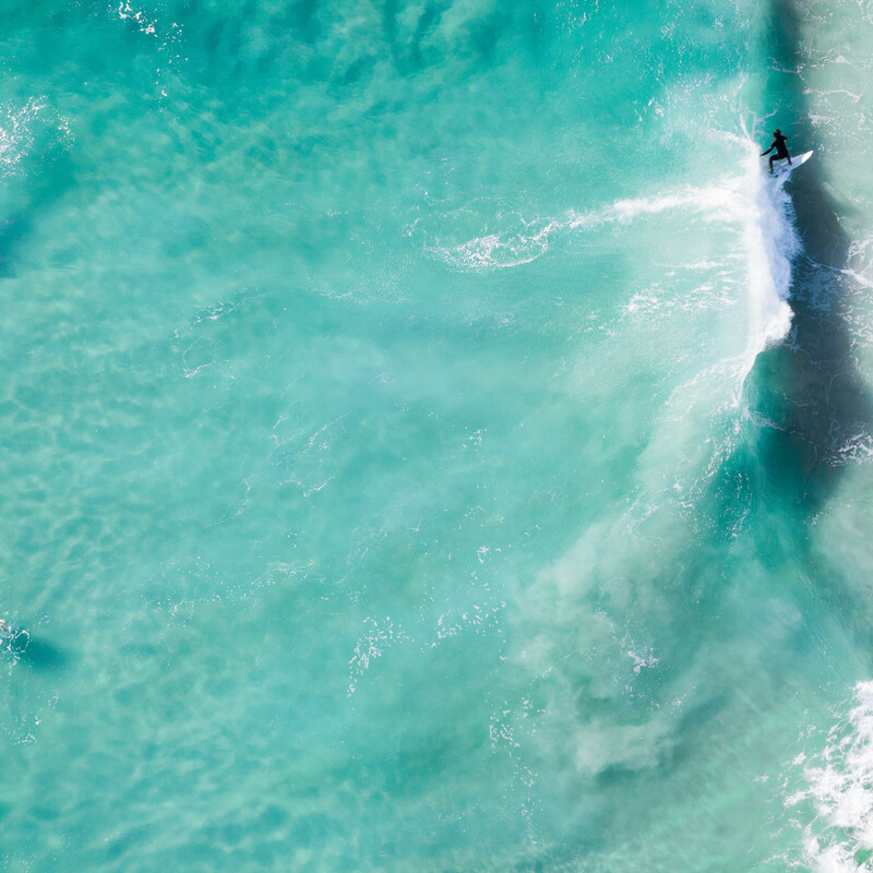 Three surfers in the water from a bird's eye view