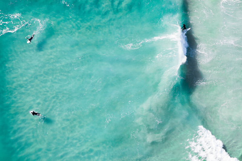 Three surfers in the water from a bird's eye view