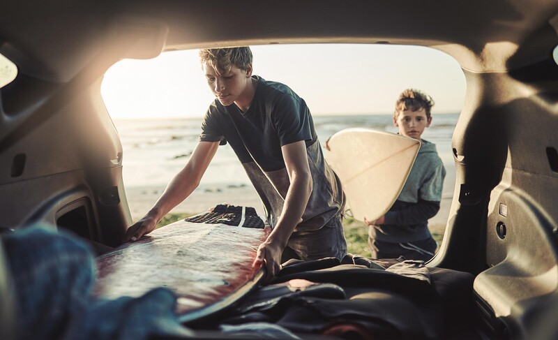 Zwei Personen laden Surfboards in ein Auto