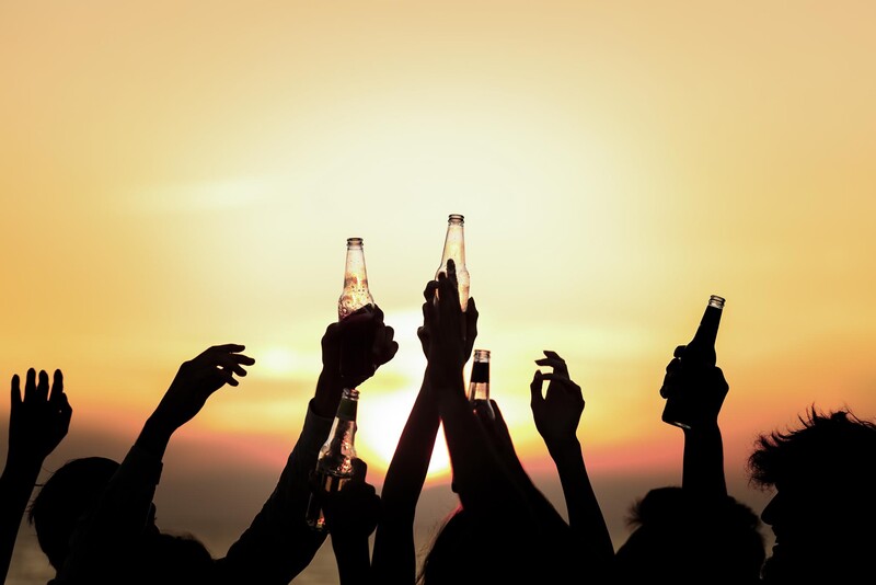 Personen bei feierlicher Abendstimmung mit Getränken beim Sonnenuntergang